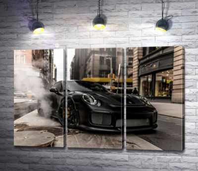 Угольно-черный автомобиль Порше (Porsche) 911 среди улицы старого города
