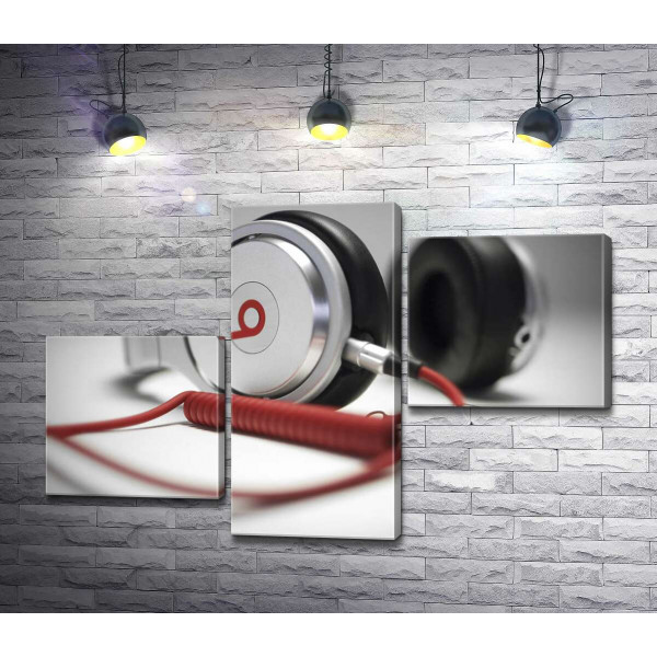 Тонкі форми білого корпусу навушників Beats у поєднанні із завитками червоного провода