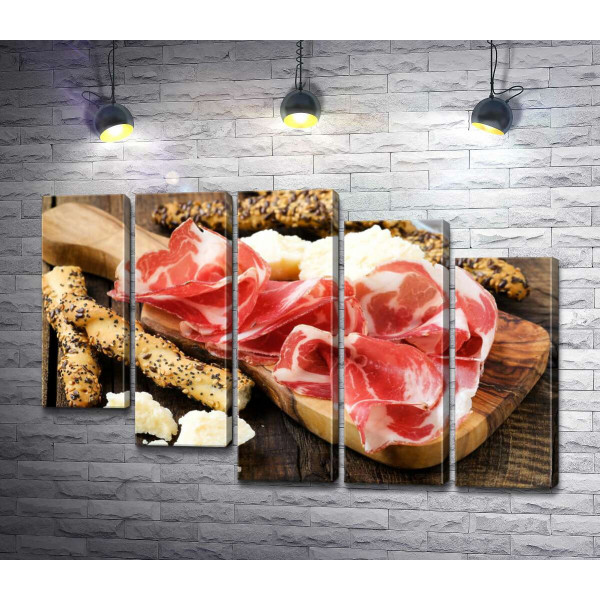 Прозорі скибочки іспанського хамону з традиційними італійськими хлібними паличками грисині та шматочками білого сиру