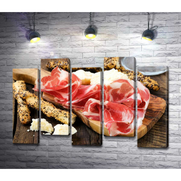 Прозорі скибочки іспанського хамону з традиційними італійськими хлібними паличками грисині та шматочками білого сиру