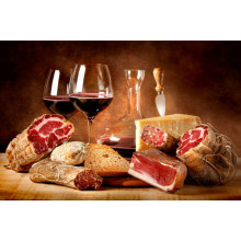 Насичене червоне вино в оточені в'яленого м'яса із сиром та скибкою хліба