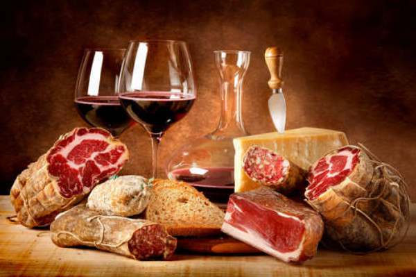 Насыщенное красное вино в окружении вяленого мяса с сыром и ломтиком хлеба