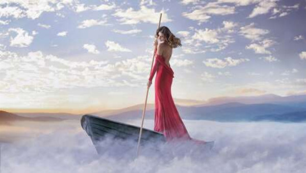 Девушка в соблазнительном платье плывет туманным озером на лодке
