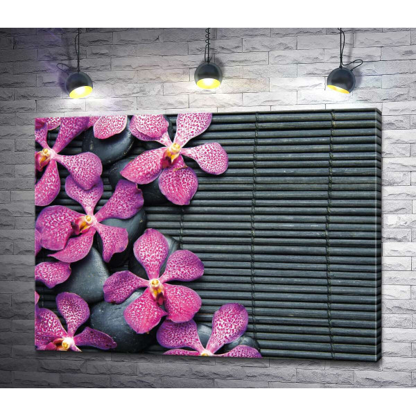 Узор красочных орхидей и черных камней на бамбуковом коврике