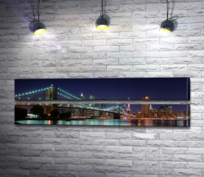 Гирлянды фонарей Бруклинского моста (Brooklyn Bridge) отражаются в водах пролива Ист-ривер (East River)