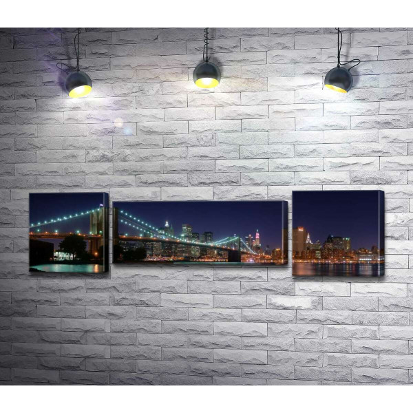 Гірлянди ліхтарів Бруклінського мосту (Brooklyn Bridge) відбиваються у водах протоки Іст-рівер (East River)