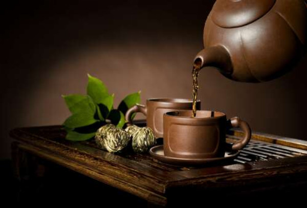 Горячий травяной чай наполняет стилизованные чашки