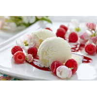 Шарики ванильного мороженого на тарелке с ягодами малины и нежными цветами