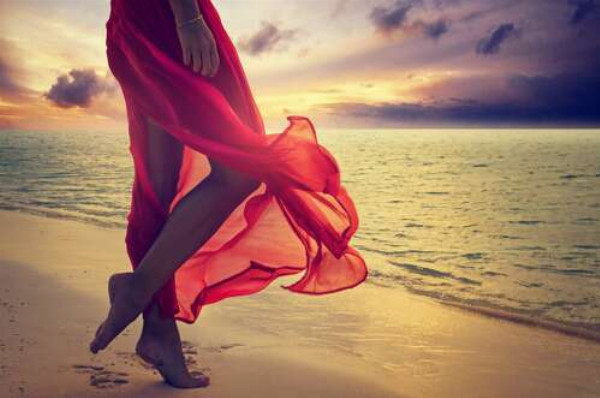 Червона тканина прозорої сукні розвіваються від морського бризу
