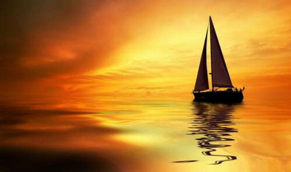 Темный силуэт яхты выделяется на оранжевом слиянии моря и неба