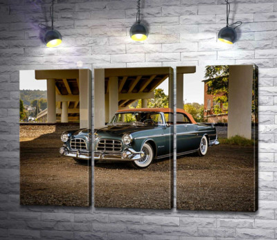 Темный автомобиль кабриолет Chrysler 1955 стоит в тени моста