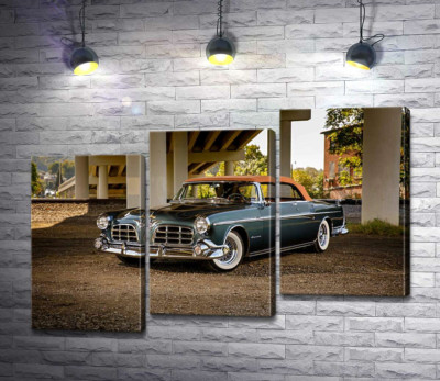Темный автомобиль кабриолет Chrysler 1955 стоит в тени моста