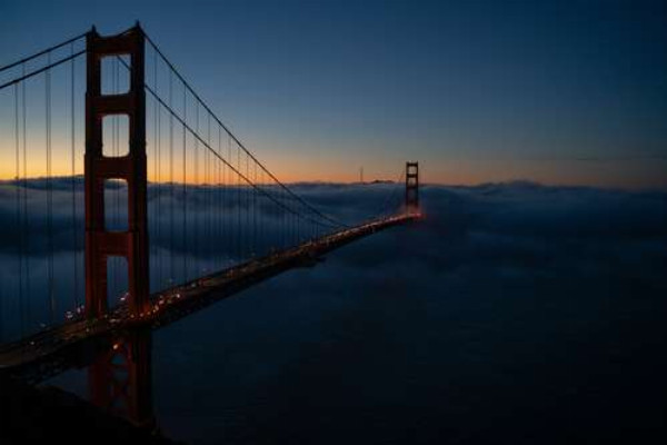 Красный силуэт моста растворяется в утреннем тумане