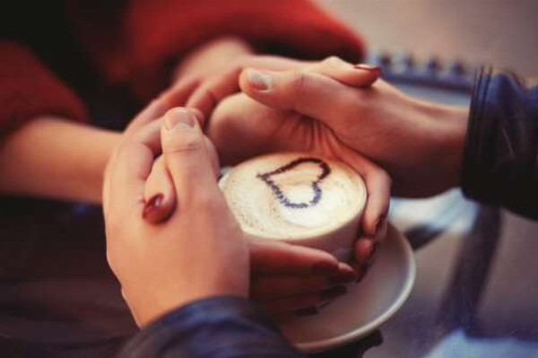 Тепло чашки с кофе согревает руки влюбленных