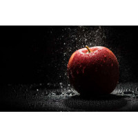 Прозрачные капли воды падают на красную поверхность яблока