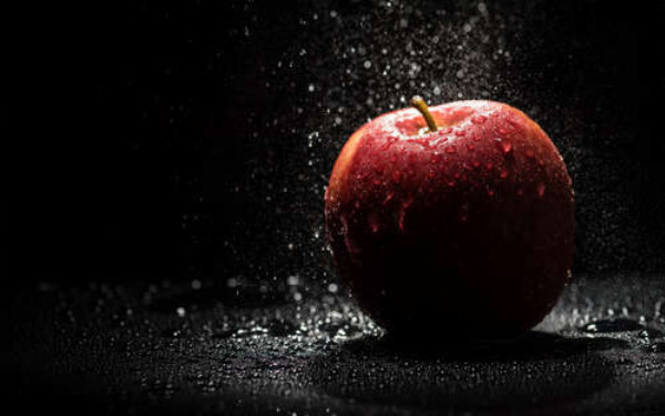 Прозорі краплі води падають на червону поверхню яблука