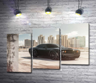 Черный автомобиль Dodge Challenger Hellcat на фоне домов