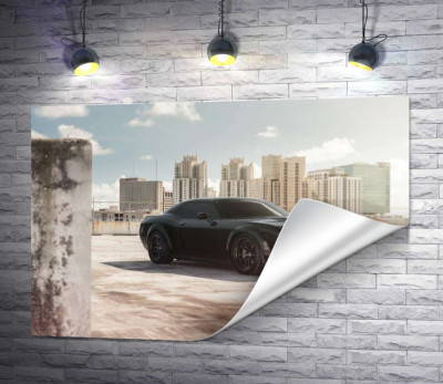 Черный автомобиль Dodge Challenger Hellcat на фоне домов