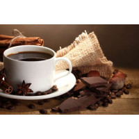 Чашка кави в оточенні прянощів, шоколаду та горіхів