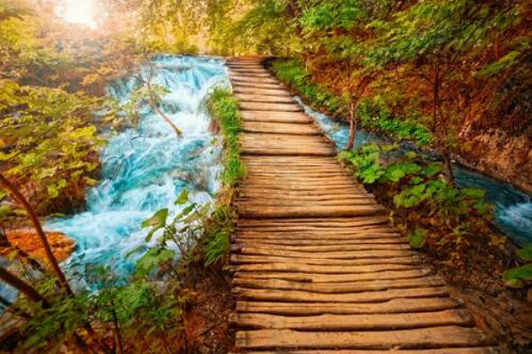 Деревянный мостик тянется над бурным водопадом