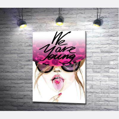 Девушка с леденцом в розовой шляпе с надписью "we are young"