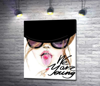 Девушка с леденцом в черной шляпе с надписью "we are young"
