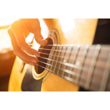 Искусные пальцы музыканта перебирают струны гитары