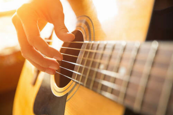 Искусные пальцы музыканта перебирают струны гитары