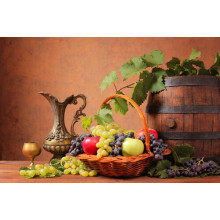 Наполненная яблоками и виноградом корзина в окружении бочки и кувшина