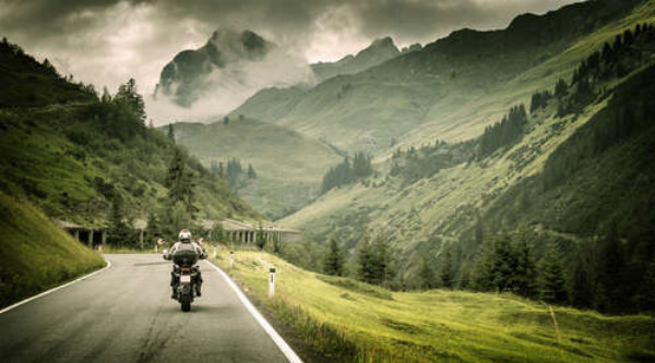 Мотоциклист едет по извилистой горной дороге