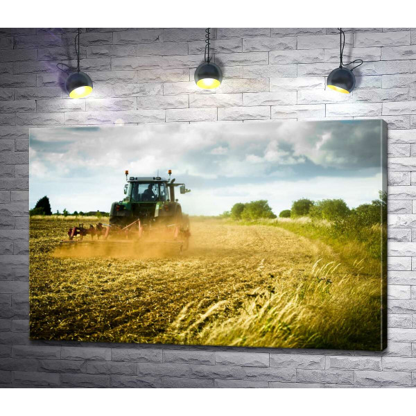 Трактор пашет землю в поле