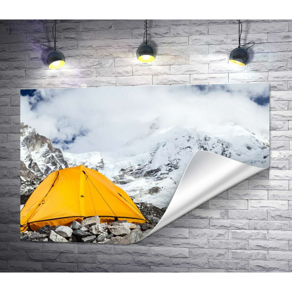 Желтая палатка стоит у заснеженной горной вершины