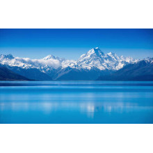 Засніжені гірські вершини височіють над блакитним озером