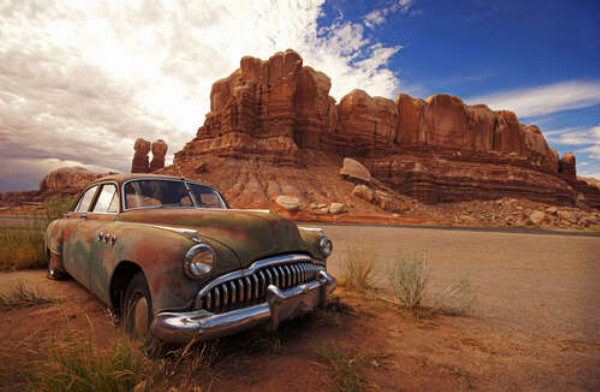 Забытый ретро автомобиль стоит на обочине дороги среди пустыни