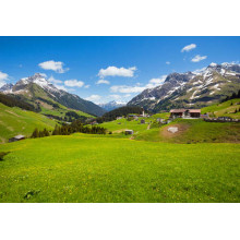 Маленькая деревня стоит среди зеленых сочных альпийских лугов