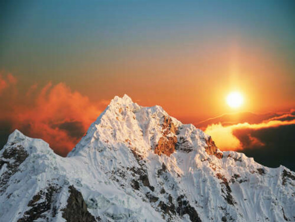 Солнечные лучи окрашивают снег на вершине горы в нежные оттенки