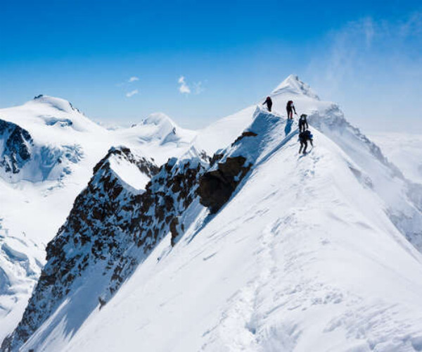 Альпинисты идут по острому хребту горной вершины