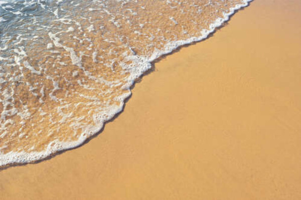 Прозрачная волна пенится на песчаном берегу