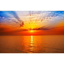 Помаранчеве сонце утворює арку променів у небі над морем