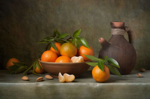 Соковиті мандарини в тарілці поряд з глиняним глечиком