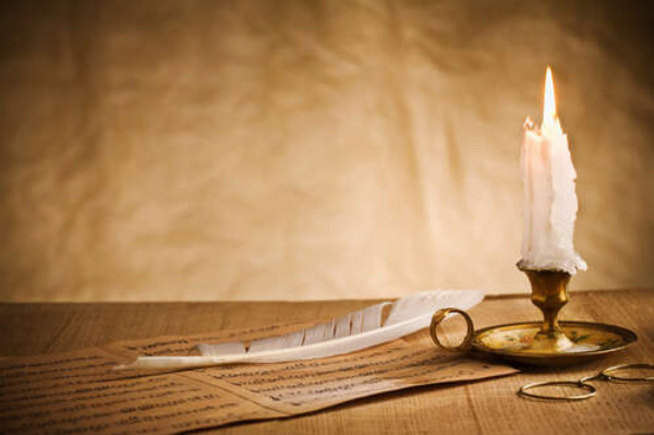 Теплый огонек белой свечи освещает письмо и перо