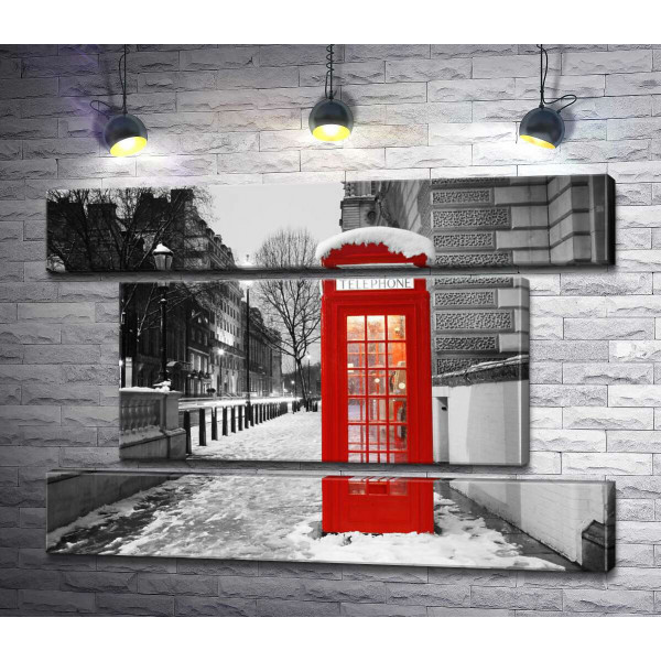 Телефонна будка стоїть на вечірній вулиці засніженого Лондона