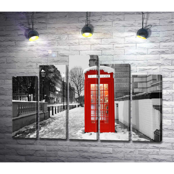 Телефонна будка стоїть на вечірній вулиці засніженого Лондона