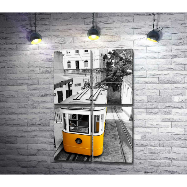 Маленький жовтий трамвай спускається по вузенькій вулиці