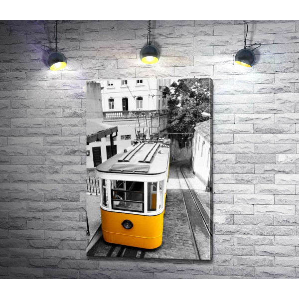 Маленький желтый трамвай спускается по узенькой улице