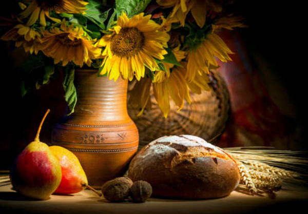 Жовтий букет соняшників у глиняному глечику поряд із продуктами