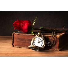 Старовинна книга прикрашена кишеньковим годинником та бутоном троянди