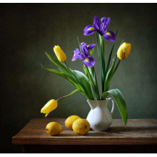 Весняна свіжість ірисів та тюльпанів у вазі біля жовтобоких лимонів