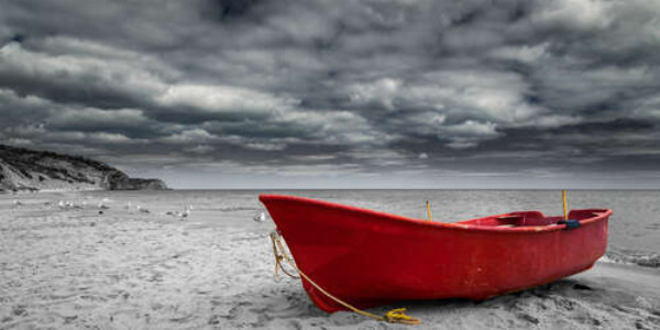Красная лодка ждет прилива на пляжном песке