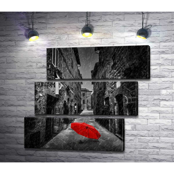 Червона парасолька лежить на дощовій вулиці старого міста